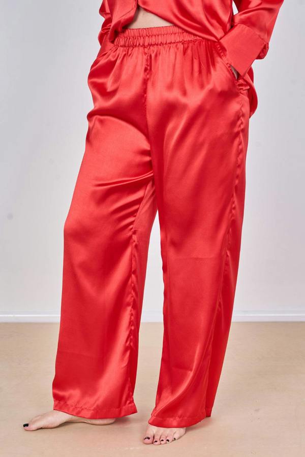 Person wearing red satin pajama pants on a plain background