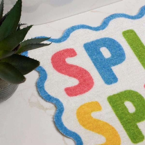 Colorful 'SPA' rug on a marble surface with a plant.