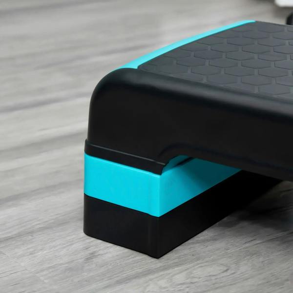 Close-up of aerobic step corner: black deck with blue edge and textured surface