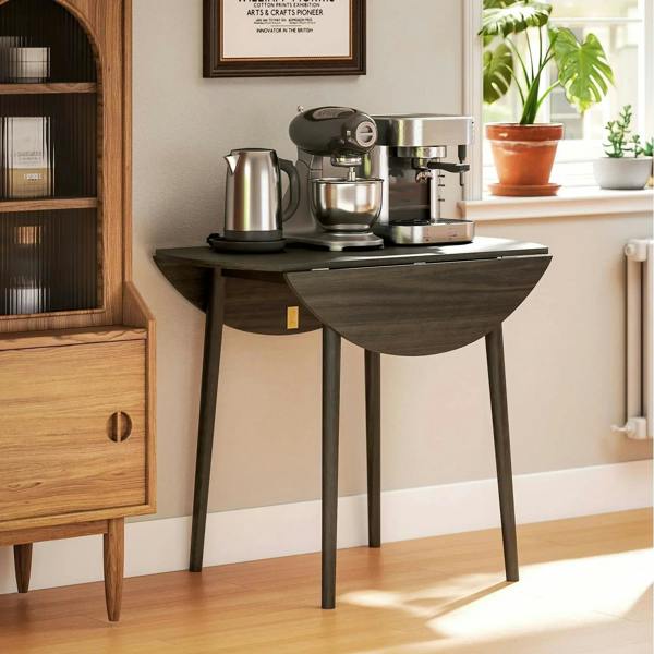 Grey round drop-leaf dining table with wood legs, used as a kitchen coffee station
