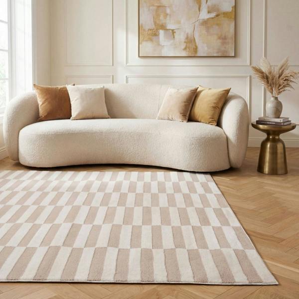 Beige sofa with decorative pillows in a living room setting with a checkered rug.