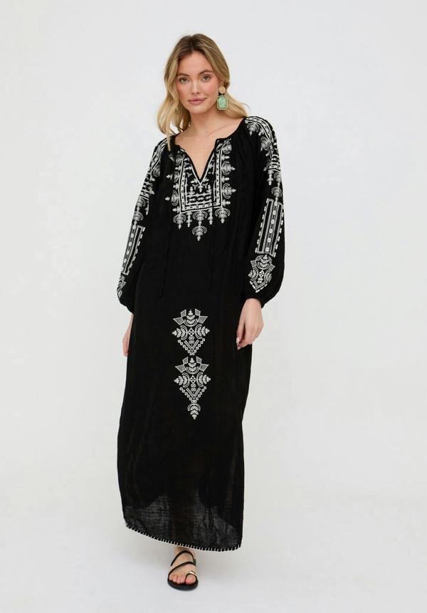 Woman wearing a black dress with white embroidery on a white background