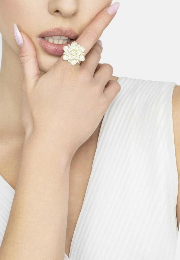 Woman wearing a gold floral ring on a white background