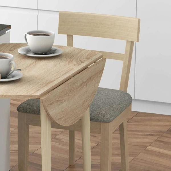Close-up of round drop-leaf dining table edge in natural wood with tapered leg support