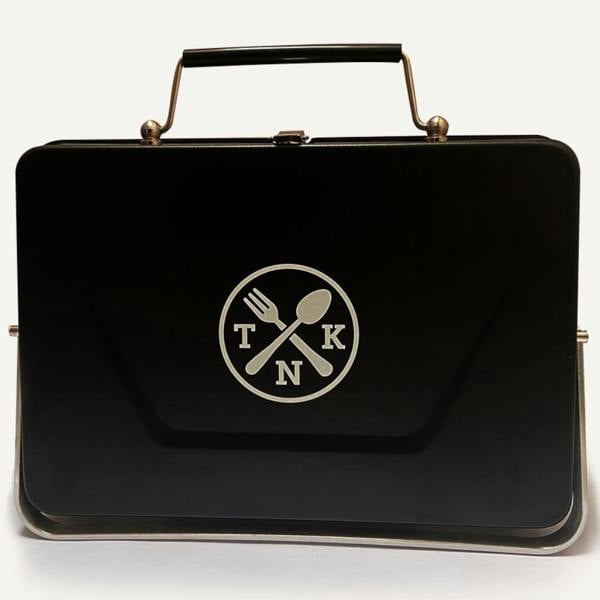 Portable Notebook BBQ folded flat into a briefcase shape with a carrying handle.