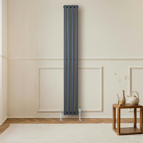 Anthracite grey oval single column radiator, 1800 x 240mm, mounted on a wall with a stylish wooden table and decor nearby