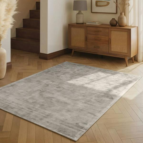 Gray rug on a wooden floor with a wooden sideboard in the background