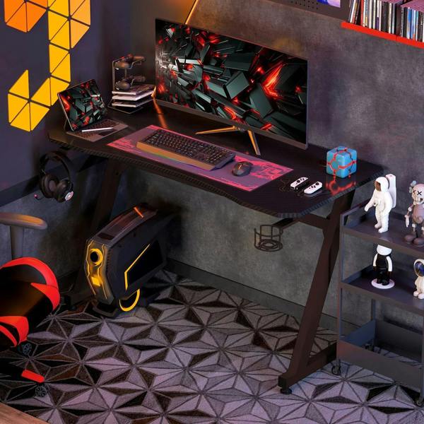 Black gaming desk with dual monitor setup, keyboard tray, and headphone hook