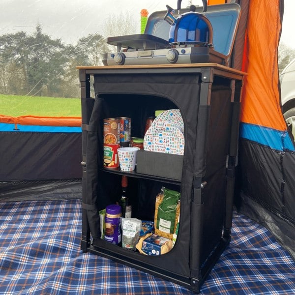 The OLPRO Bamboo Cooking Table with plates, cutlery and food in it in a campervan awning.