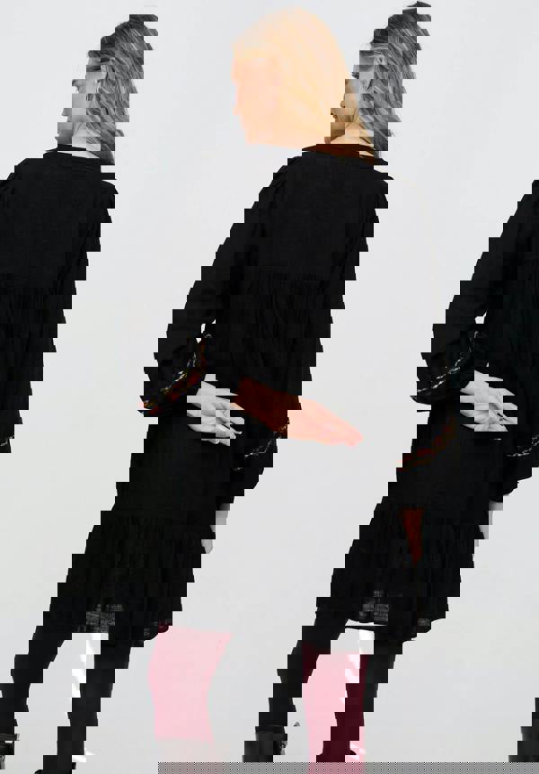 Woman wearing a black dress with long sleeves and red accents on a white background