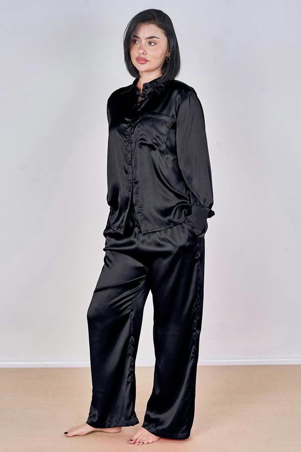 Woman wearing black satin pajamas against a plain background