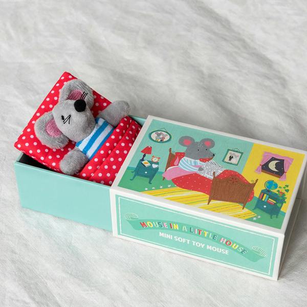 A mini grey plush mouse tucked into a red polka dot bed inside a teal illustrated matchbox house.