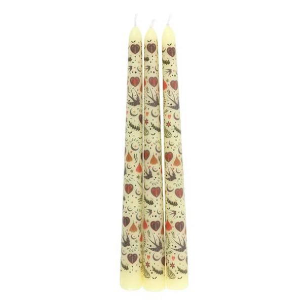 Set of three cream taper candles with hearts, birds, and star pattern