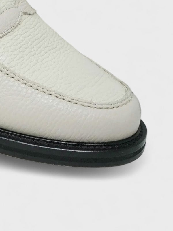 Close-up of a white shoe with a black sole on a light gray background