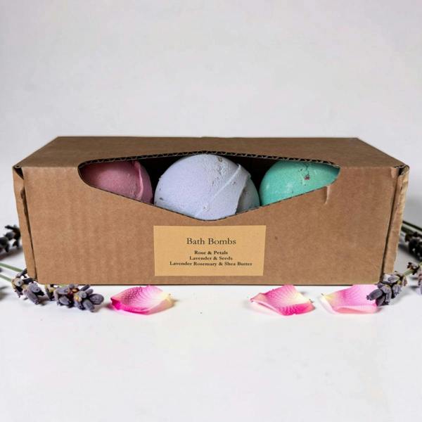 Three bath bombs in a cardboard box with a label, surrounded by decorative petals on a light background.