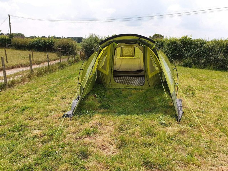 An image of the Abberley XL Extension by Olpro Front view, attached to the Abberley XL Tunnel Tent on a camping field with the front open and window blind open.