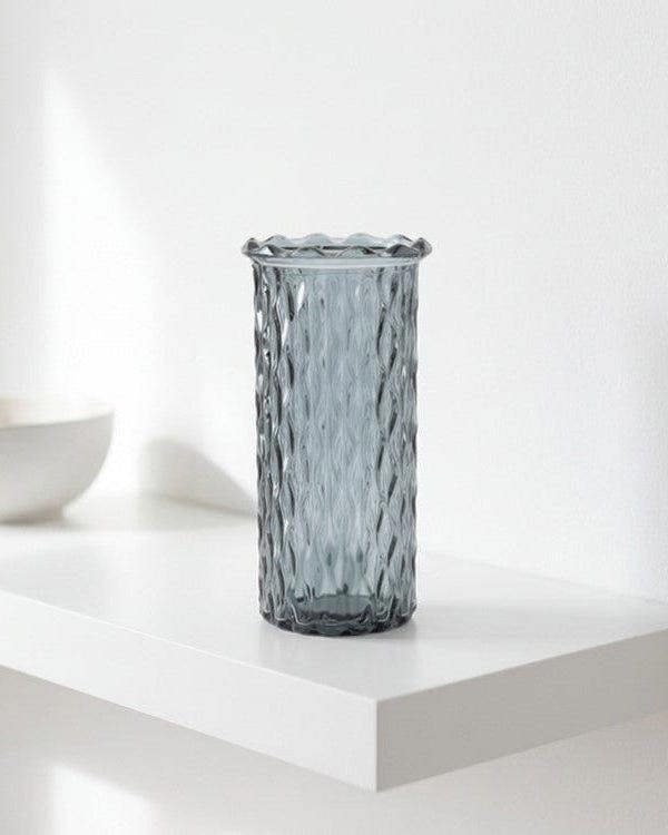 Grey textured vase on a white surface with a white bowl in the background
