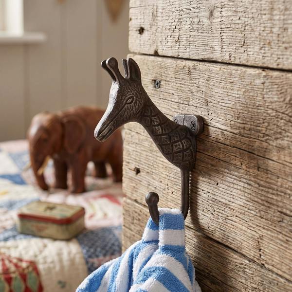Antique cast iron giraffe-shaped single hook mounted on a rustic wooden wall, featuring detailed craftsmanship and vintage charm suitable for interior decor.