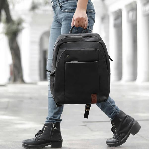 Person holding a black backpack with a blurred background