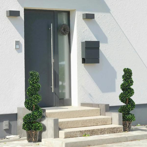 Set of 2 tall artificial spiral plants in brown pots with dense green foliage outdoors