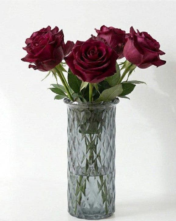 Grey glass vase with red roses on a white background