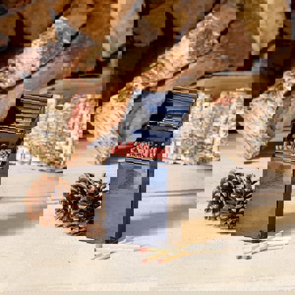 Lifestyle image of Valiant Match Tidy open on hearth with logs and pinecones 
