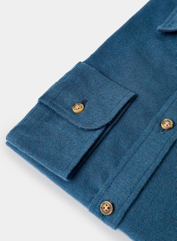 Close-up of a blue fabric with gold buttons on a white background