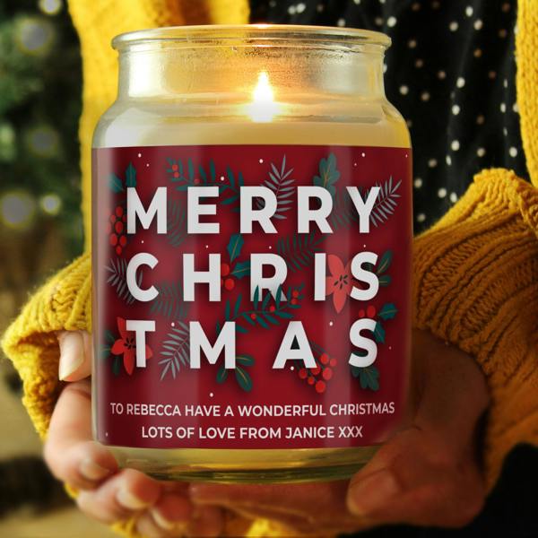 Large personalised Christmas jar candle with red berry foliage design and custom message being held in hands.