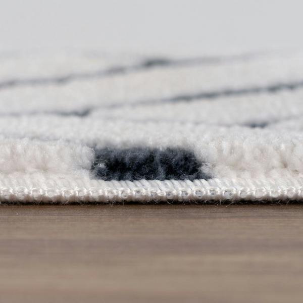 Close-up of a textured rug with a neutral color palette on a wooden floor.