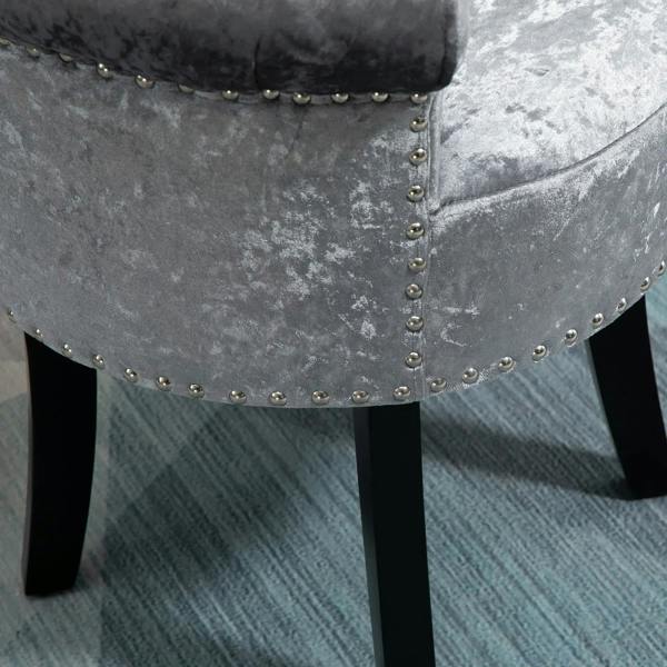 Grey upholstered side panel with studded nailhead trim on vanity stool, black legs
