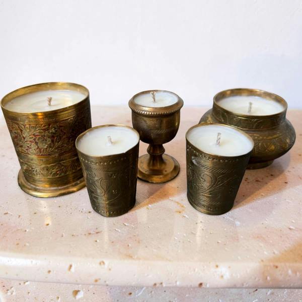 Five candles in ornate brass holders on a marble surface