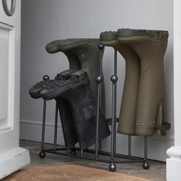 A raw metal dark grey welly stand holding green and black boots inside an entryway by Abode Home & Gifts.