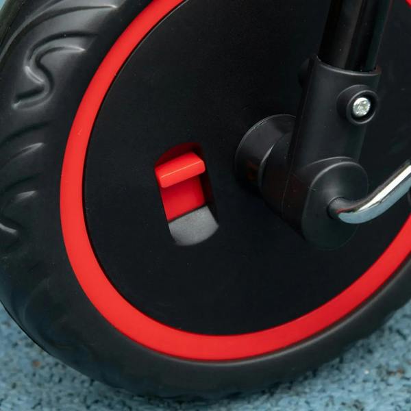 Front wheel and red fork detail on a red kids tricycle with black rim accents