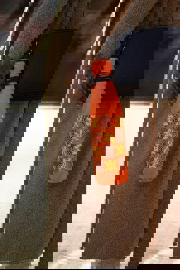 Orange bottle hanging off lady's hand bag