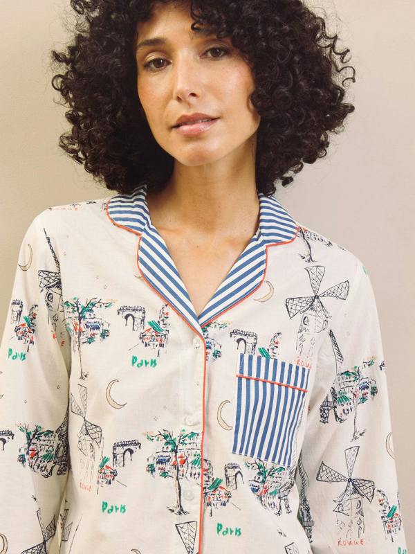 Woman wearing a navy and white Paris print pyjama with stripes set against a plain background