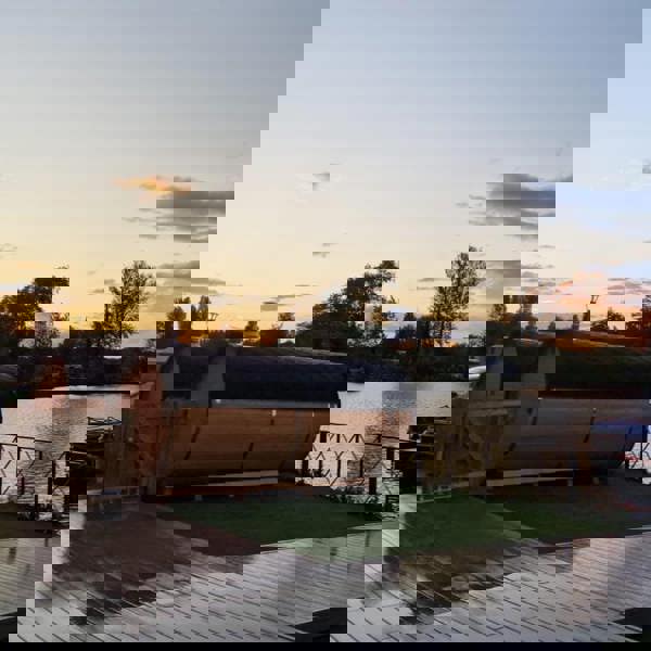 Wooden barrel saunas near a lake at sunset.