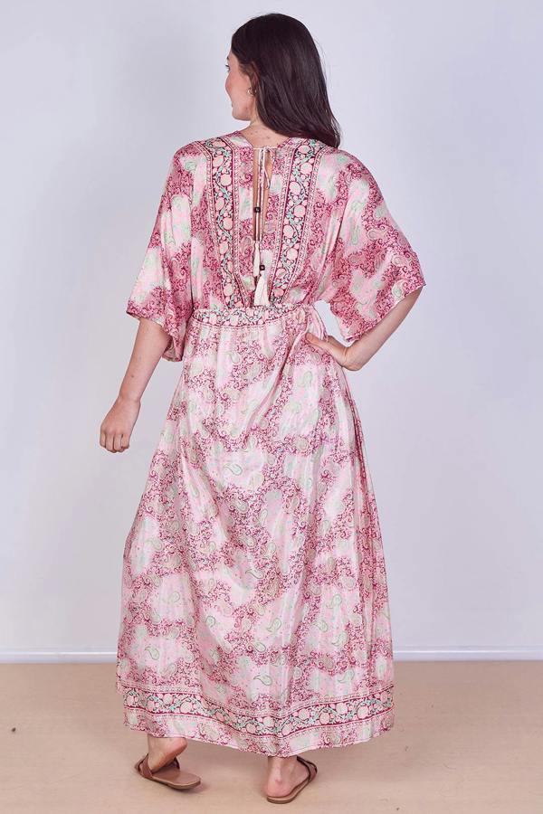 Woman wearing a pink floral dress on a plain background