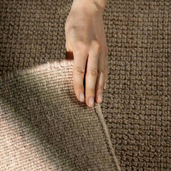 Hand touching a textured brown fabric surface