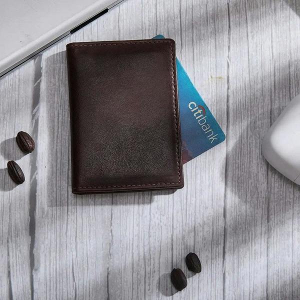 Brown leather card holder with a Citi card on a light wooden surface