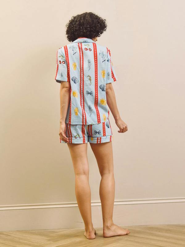 Person wearing a patterned pyjama set against a beige wall.