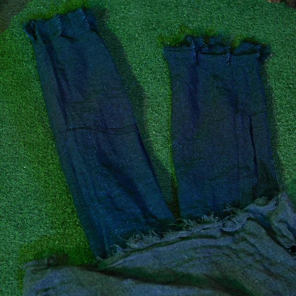 Grey tattered zombie prop legs and cloth body on green grass