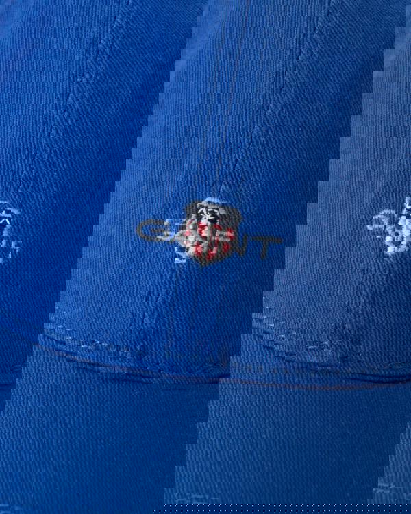 Close-up of a blue cap with GANT logo on a blue background