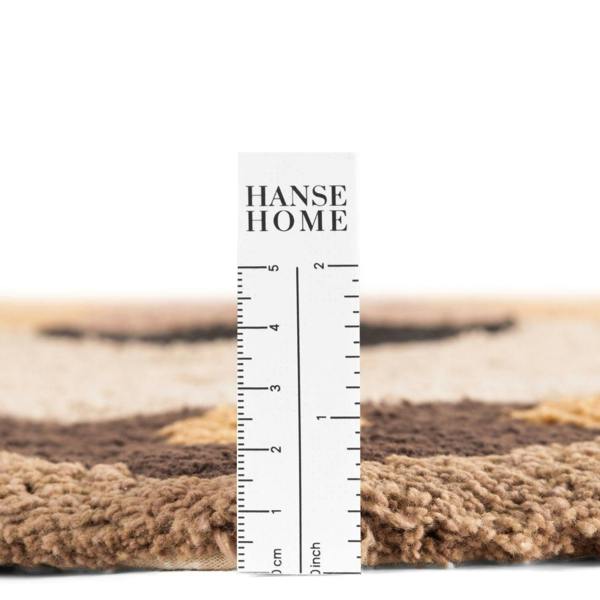Textured carpet sample with a ruler for measurement, branded 'HANSE HOME'.