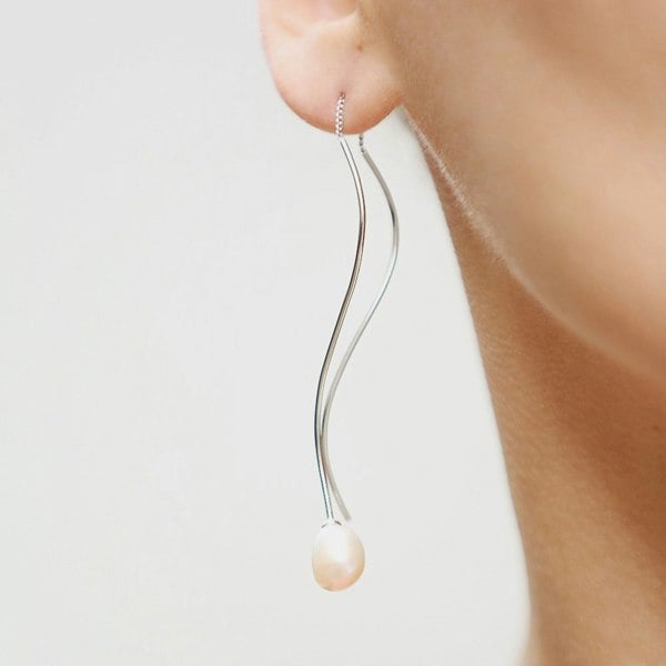 An ear with silver pearl threaders.
