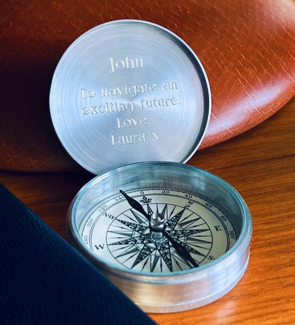 An open personalised aluminium pocket compass with a traditional dial face and a custom engraved message on the inside lid.