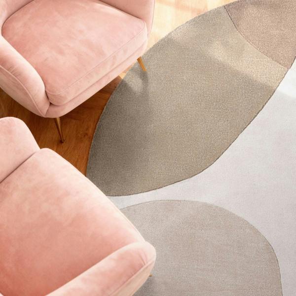 Pink chairs with a gray and beige patterned rug on a wooden floor.