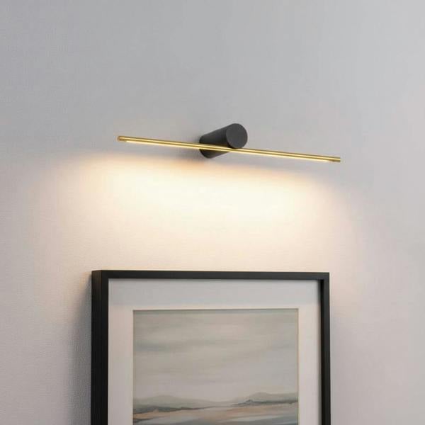 gold picture light fixture mounted over artwork on the wall 