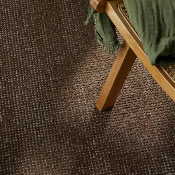 Brown textured carpet with a wooden chair and green fabric.