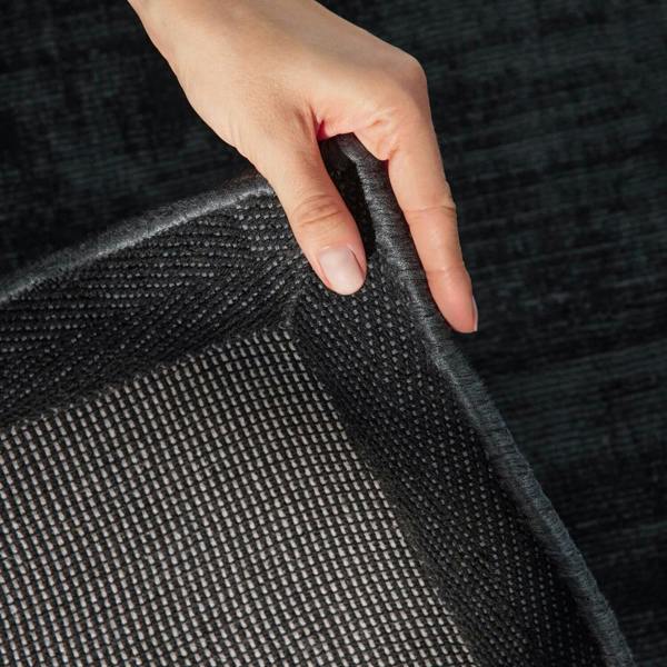 Hand touching a textured black fabric surface
