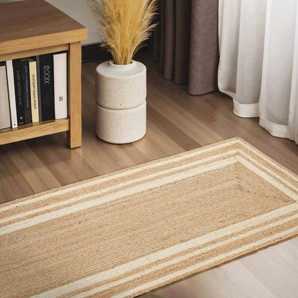 Beige striped rug on a wooden floor with a bookshelf and decorative plant in the background.